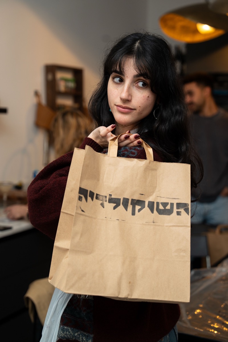 משתתפת עם שקית נייר ממותגת של השוקולדיה